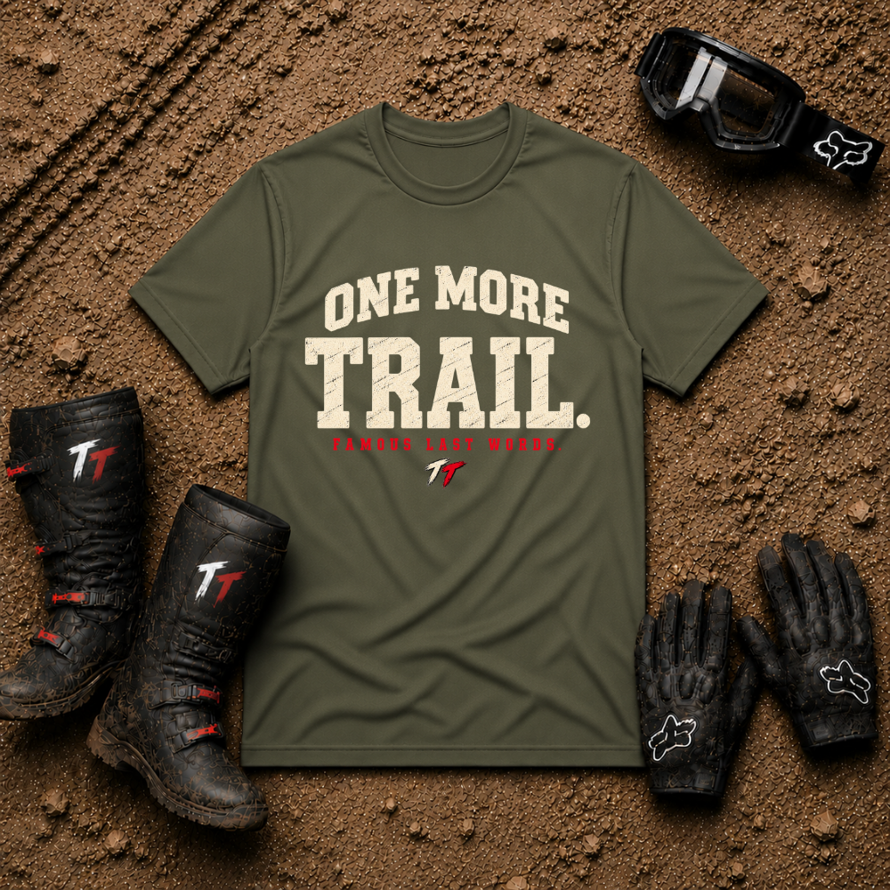 Military Green One More Trail t-shirt with vintage varsity print and 'Famous Last Words' tagline — flat lay with muddy boots, goggles, and gloves, Tire Time Offroad