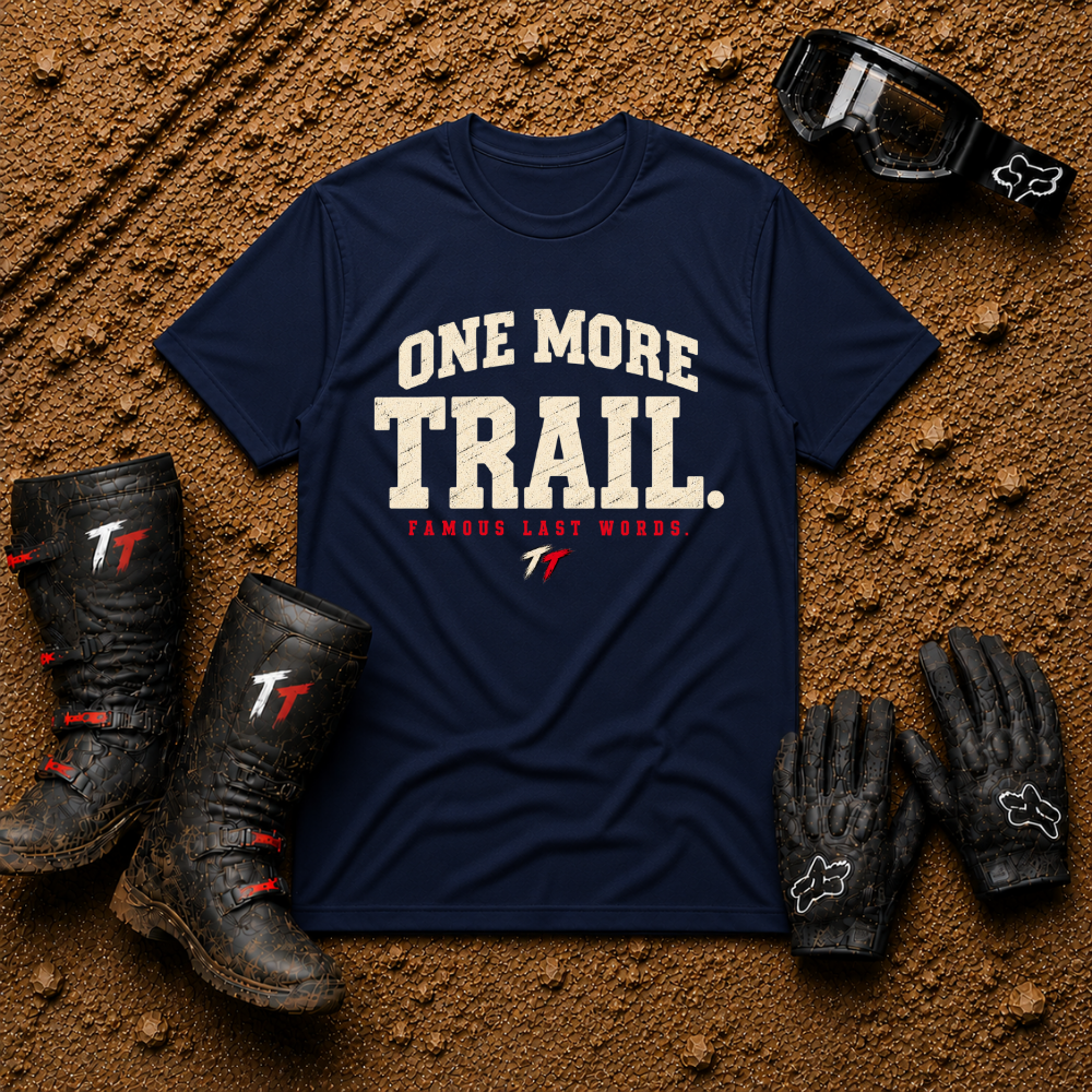 Navy One More Trail t-shirt with vintage varsity print and 'Famous Last Words' tagline — flat lay with muddy boots, goggles, and gloves, Tire Time Offroad