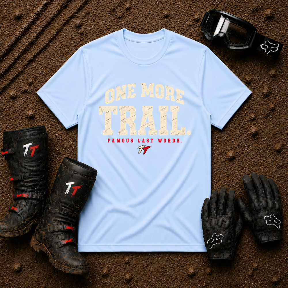 Light Blue One More Trail t-shirt with vintage varsity print and 'Famous Last Words' tagline — flat lay with muddy boots, goggles, and gloves, Tire Time Offroad